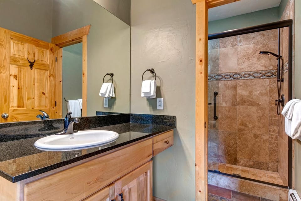 Primary ensuite bath features a granite vanity and walk-in shower with stone tile surround.