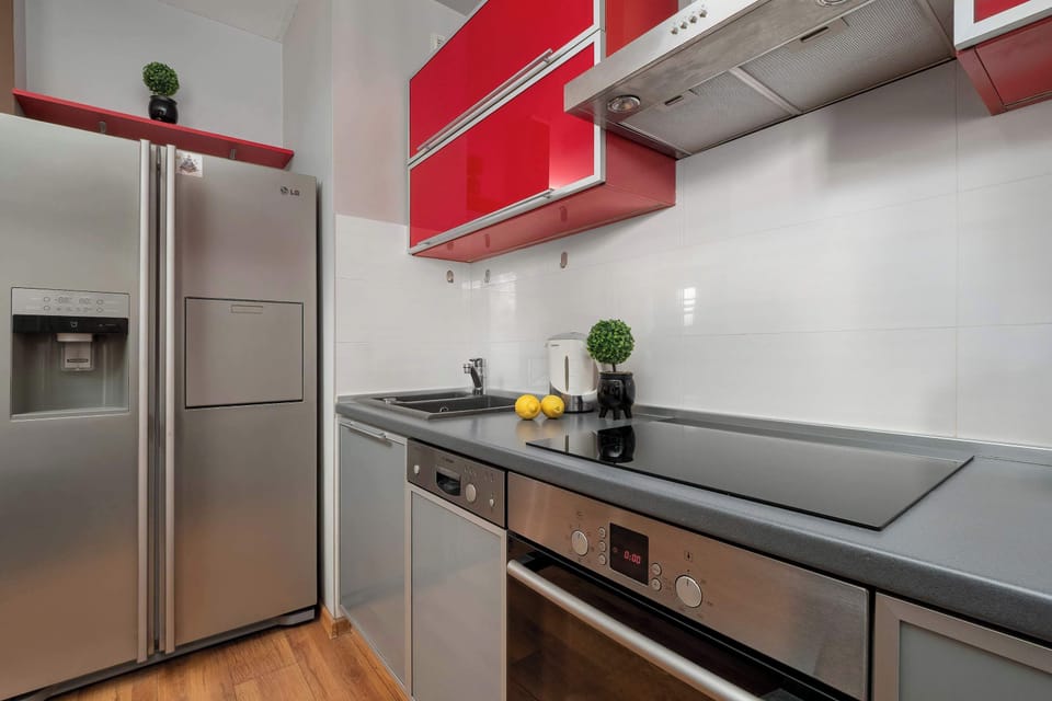 Compact modern kitchen with stainless steel refrigerator and sleek finishes.