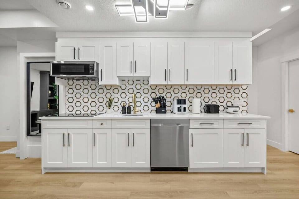 Modern kitchen featuring white cabinetry, stainless steel appliances, and geometric backsplash