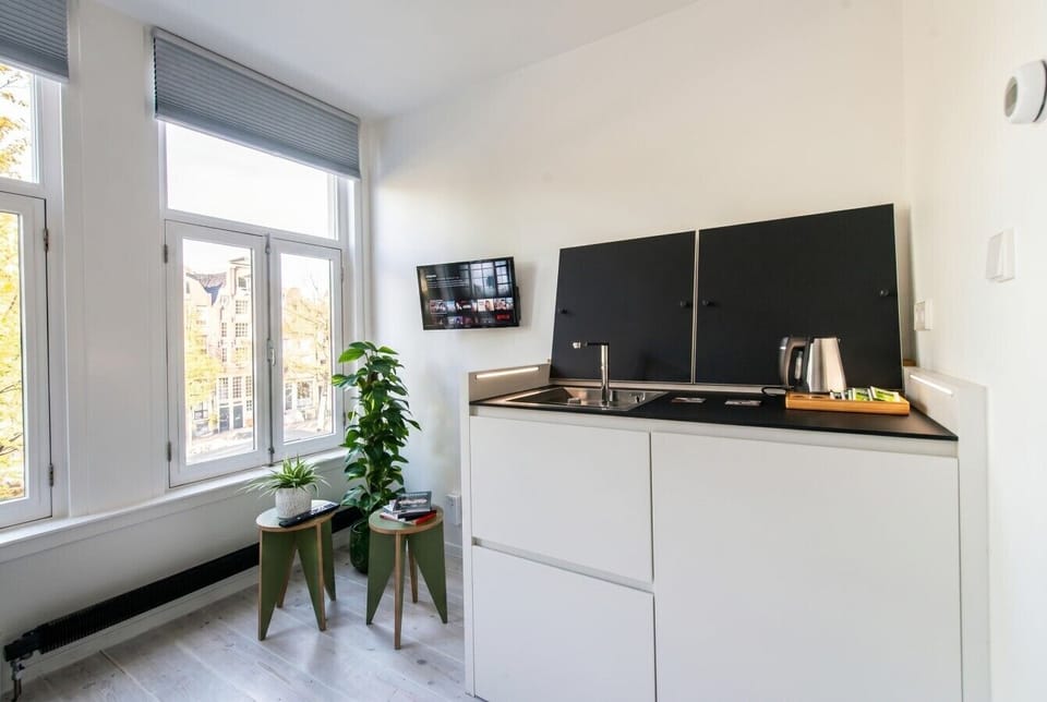 Compact kitchenette with canal-side window and morning light.