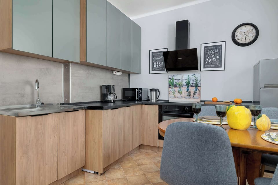 This angle of the kitchen shows the transition between the cooking area and the circular dining table. The use of grey and wood tones creates a cohesive and sophisticated aesthetic.