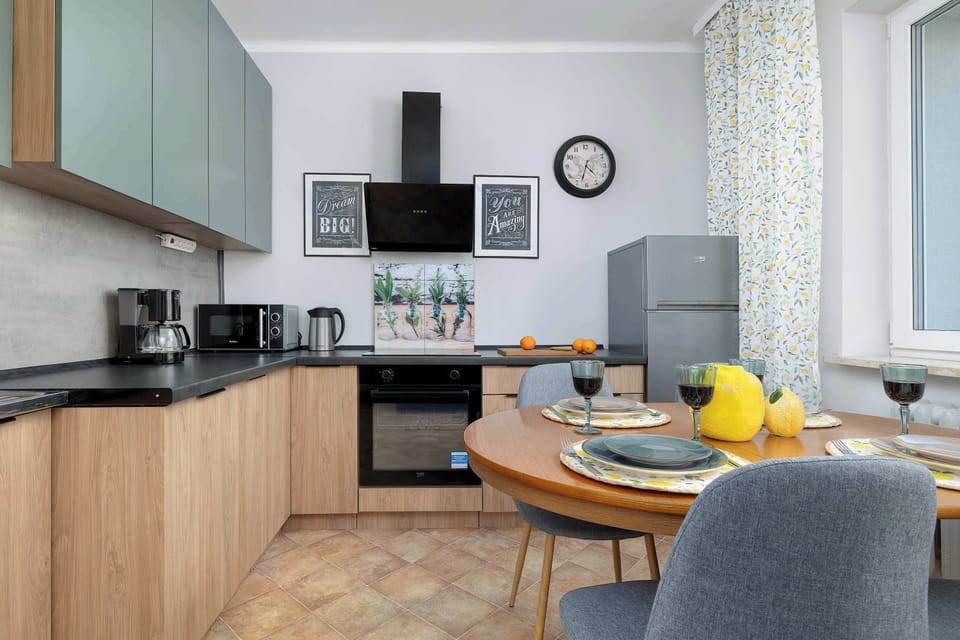 The kitchen area is equipped with integrated appliances and a black induction cooktop under a modern extractor fan. Light wood flooring complements the cabinetry and enhances the contemporary feel.