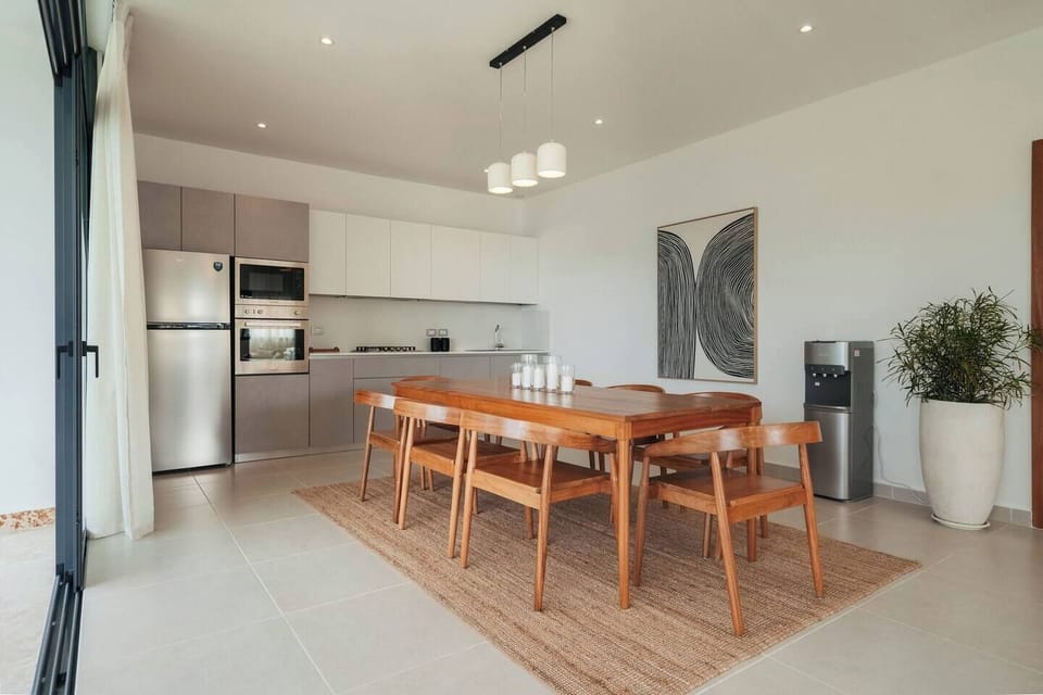 Spacious dining area with a large table and seating for six, next to a fully equipped kitchen