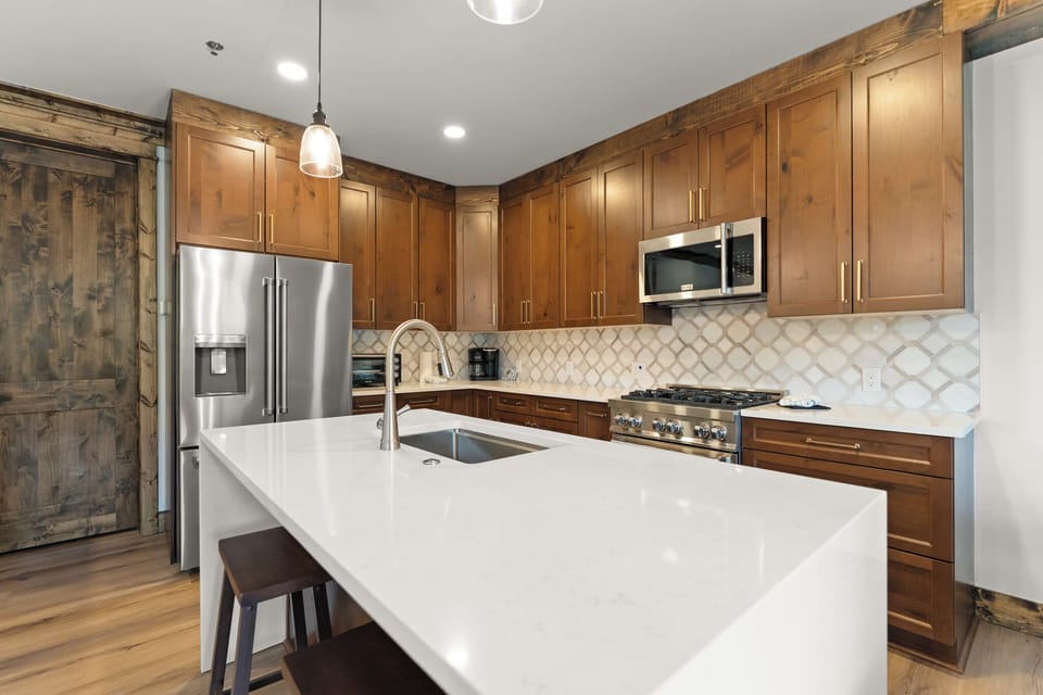 Your gourmet kitchen awaits, featuring rich wood cabinetry, sleek quartz countertops, and stainless appliances.