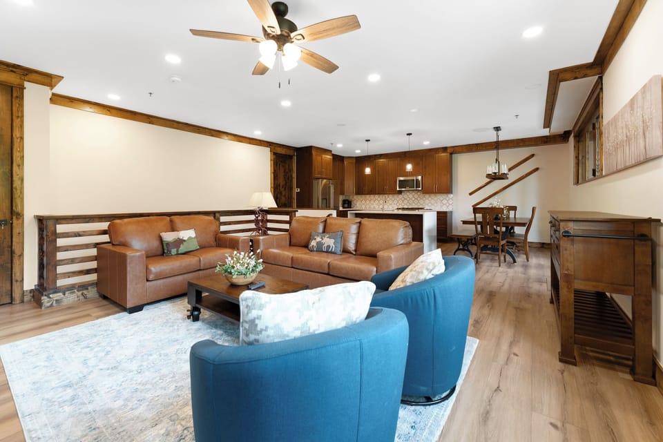 Relax in your spacious living area with warm wood accents, natural light flooding through large windows, and cozy seating perfect for unwinding after a day of adventure.