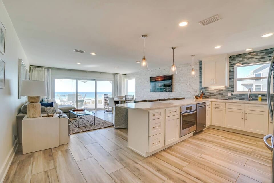 Your open-concept retreat flows seamlessly from a bright gourmet kitchen to a sun-soaked living space with stunning ocean views beyond the balcony—coastal living at its finest.