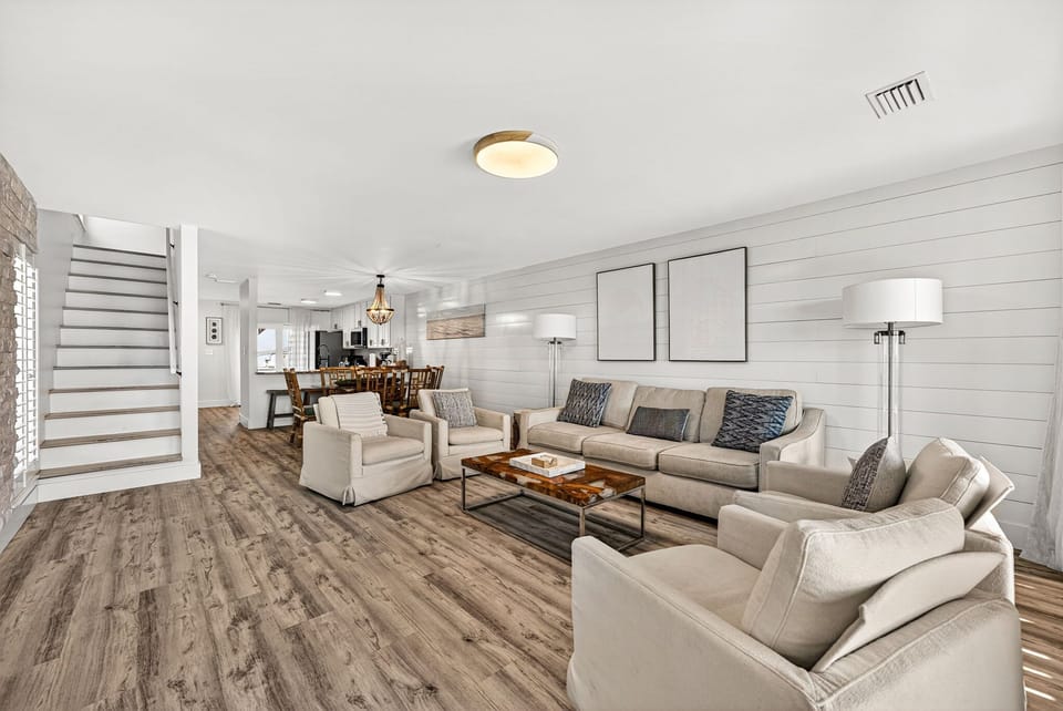 Sink into plush seating in your open-concept living area, where shiplap walls and coastal charm create a serene retreat for gathering with loved ones.
