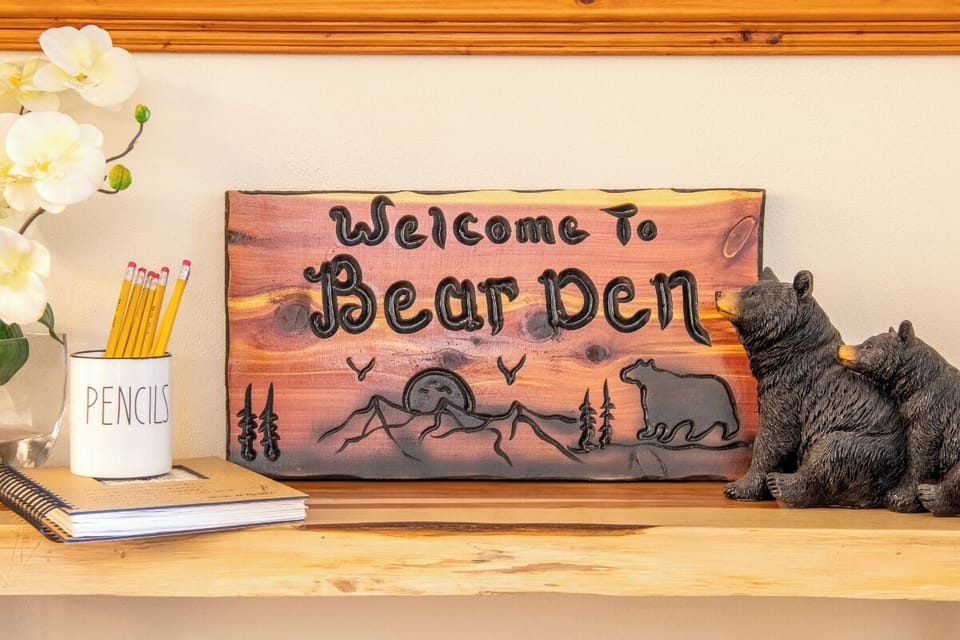Bear Den's custom carved sign welcomes you at the entrance, setting the tone for a cozy mountain retreat with charming rustic details.