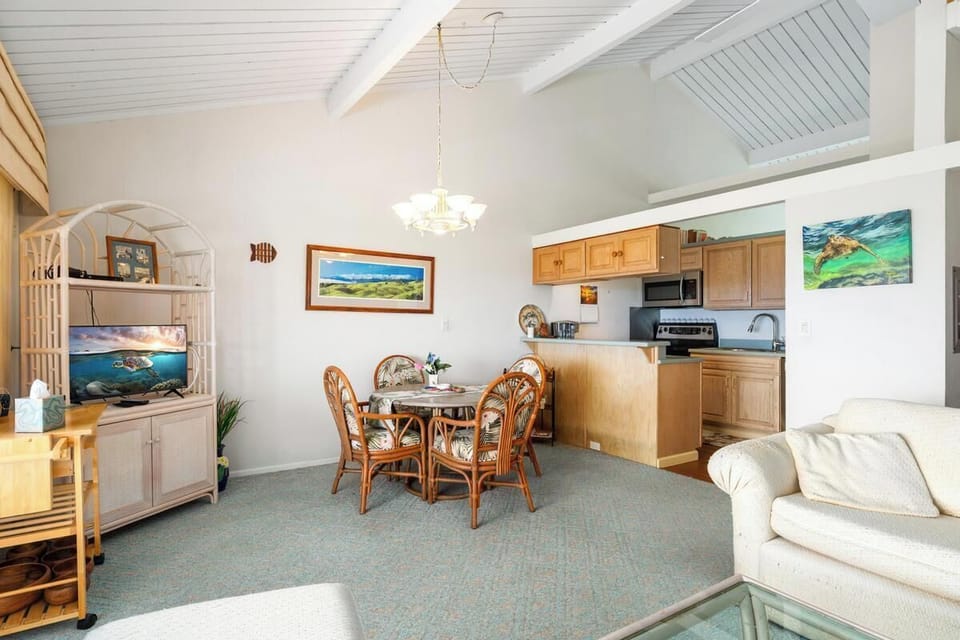 Relax in your bright, open living space where cozy seating flows into a dining nook and well-equipped kitchen. High vaulted ceilings and coastal artwork create an airy, beachy retreat perfect for unwinding after island adventures.