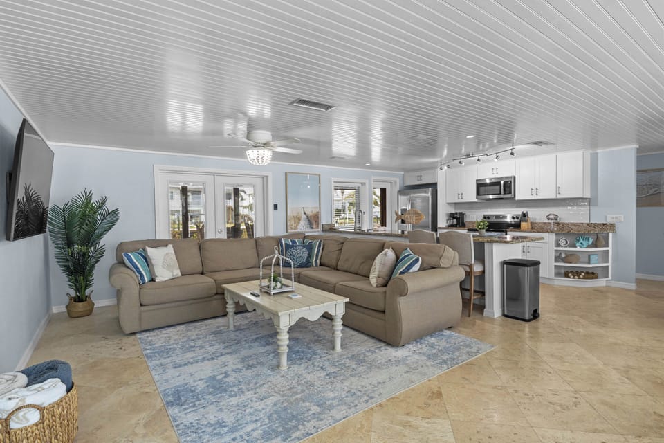 Living room with ceiling fan and large French doors to pool area