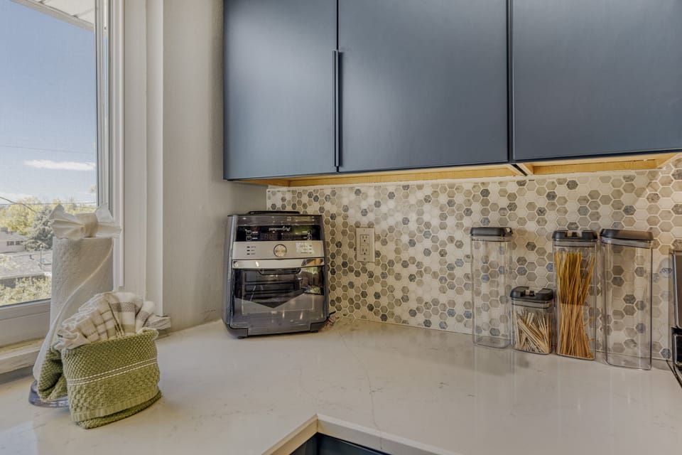 Your kitchen features modern appliances and stylish hexagonal tile backsplash, with natural light streaming through the window as you prepare your favorite meals.