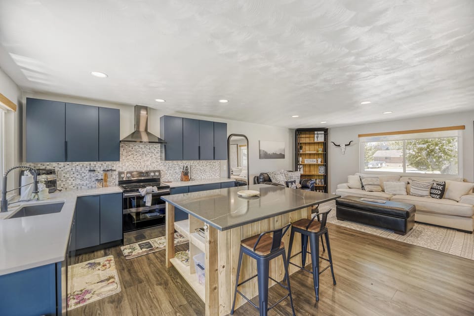 Bright, open living space where you can cook, dine, and unwind together—modern blue cabinetry, a stylish island, and cozy seating await your getaway.