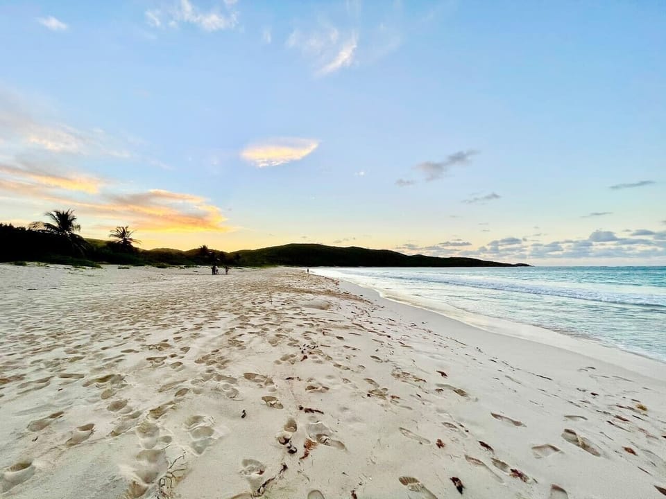 Quiet white-sand shoreline at sunset.