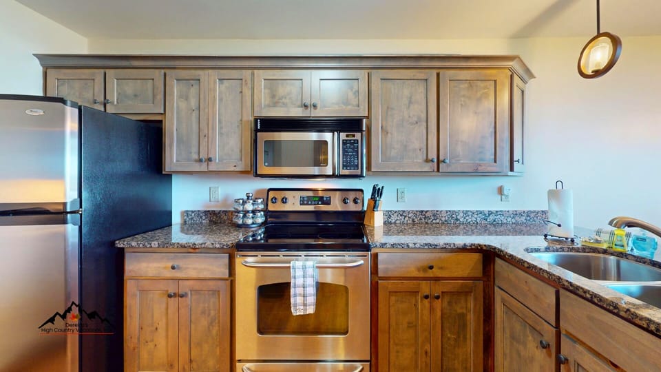 Your fully equipped kitchen features stainless steel appliances, granite countertops, and warm wood cabinetry—perfect for preparing meals during your stay.