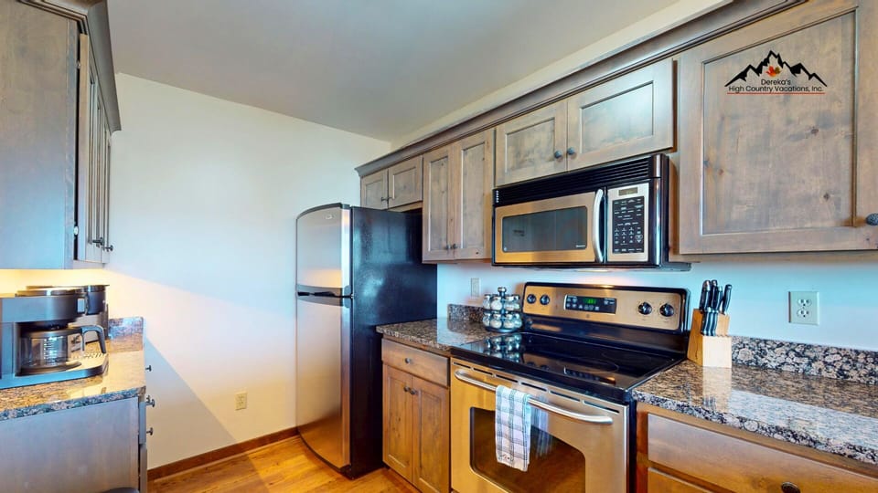 Your fully equipped kitchen features modern appliances, granite counters, and warm wood cabinetry—everything you need to prepare meals in mountain comfort.