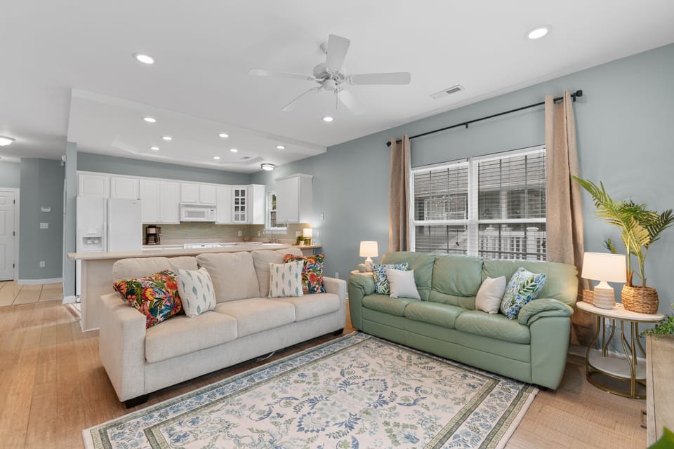 Unwind in your bright, coastal-inspired living area with plush sofas, cheerful décor, and an open layout that flows seamlessly into the fully equipped kitchen.