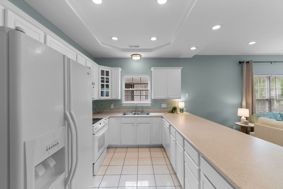 Cook and gather in your fully equipped kitchen with sleek white cabinetry, modern appliances, and soothing coastal tones that set the stage for delicious meals and easy vacation living.