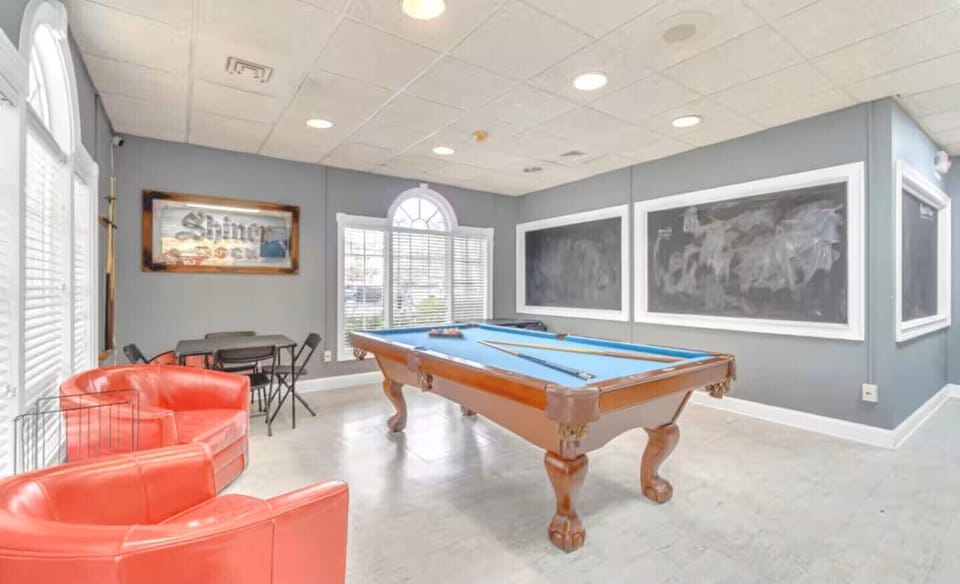 Bright game room with pool table, lounge seating, and plenty of natural light