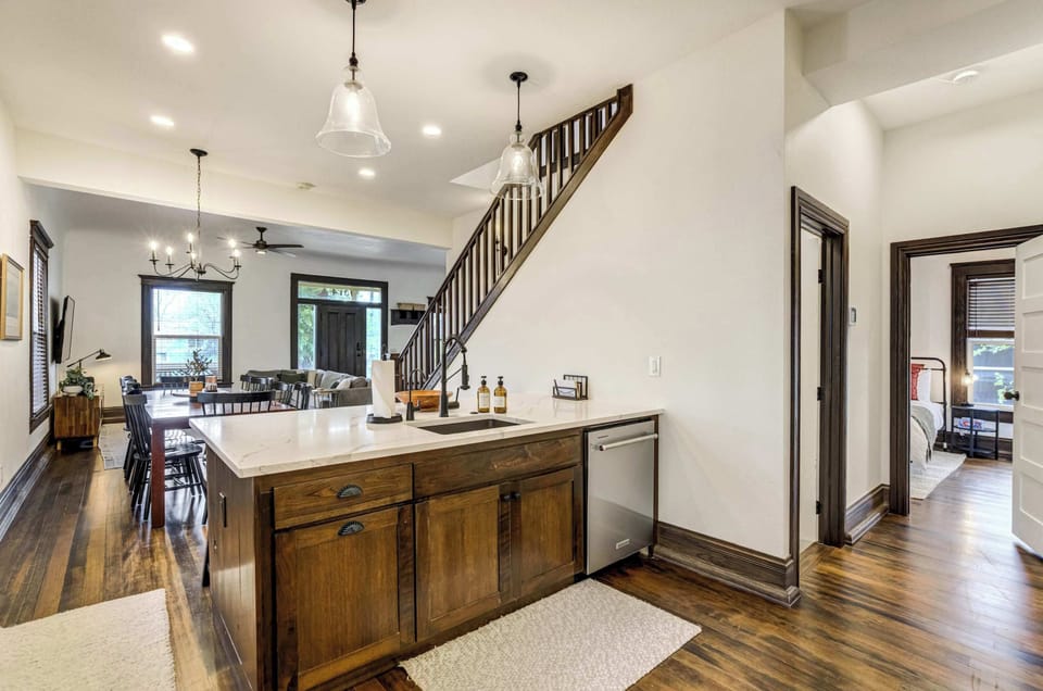 A second angle of the main level kitchen reveals dark wood cabinetry on the island, pendant lighting, and a direct sightline to the bedroom hallway, showcasing how seamlessly the space connects throughout.