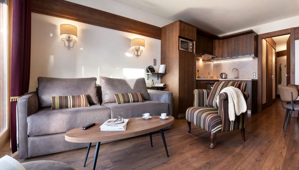 Open-plan lounge with grey sofa, striped cushions, and warm wood floors — settle in after a day of hiking in the Belleville Valley.