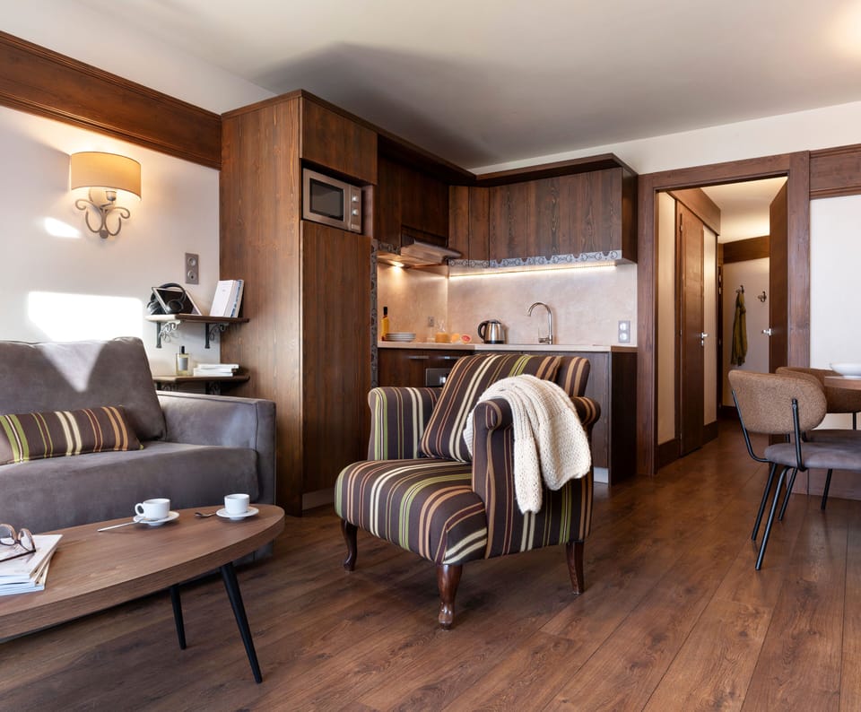 The living area looking toward the balcony door, with striped armchair and wood-panelled walls typical of the Kashmir-inspired décor throughout.