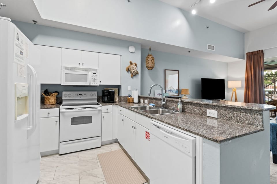 Fully functional kitchen with fridge, microwave, range, dishwasher, and coffeemaker.