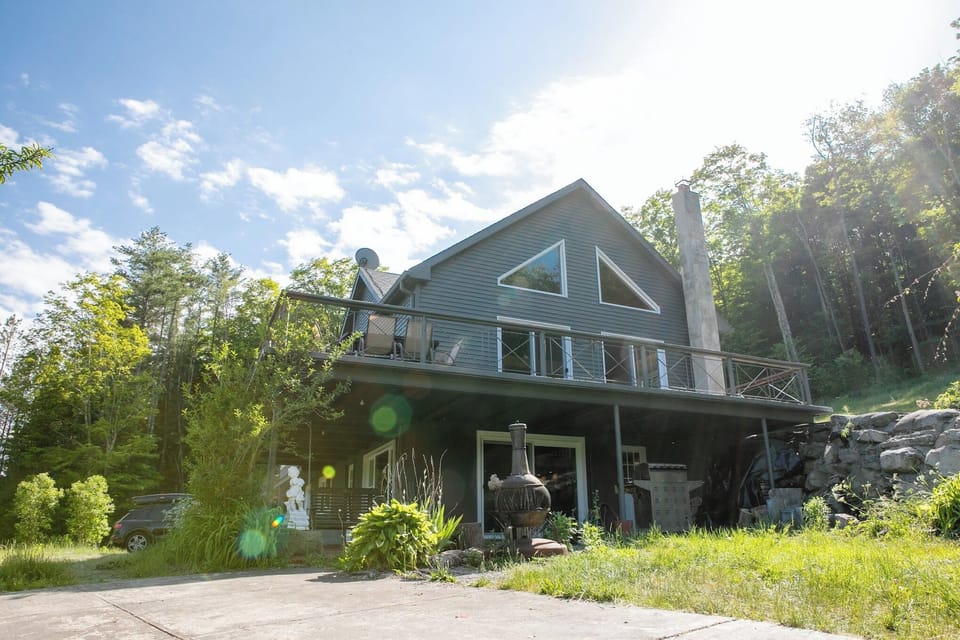 Secluded mountain lodge featuring high ceilings, a massive deck, and lush yard.