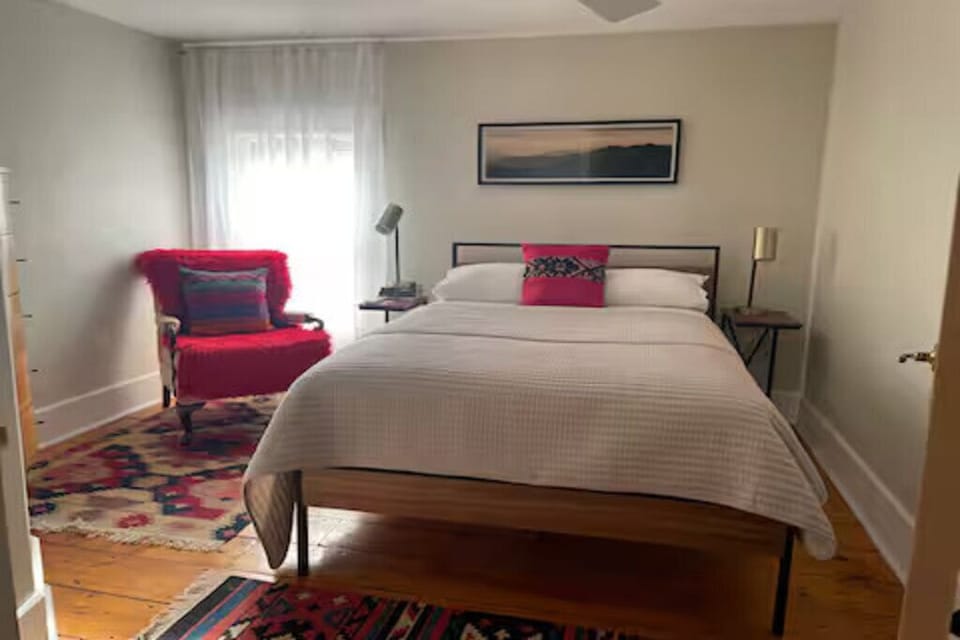 Peaceful, well-lit bedroom featuring vintage decor and a comfy queen bed.
