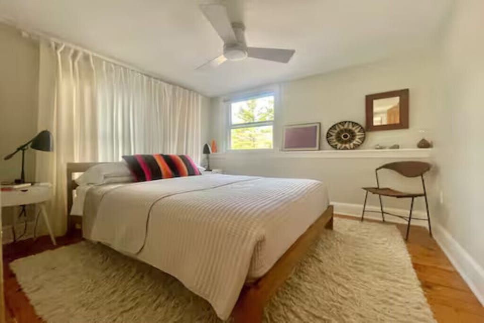 Sunlit, cozy bedroom boasting a plush area rug and minimalist decor.