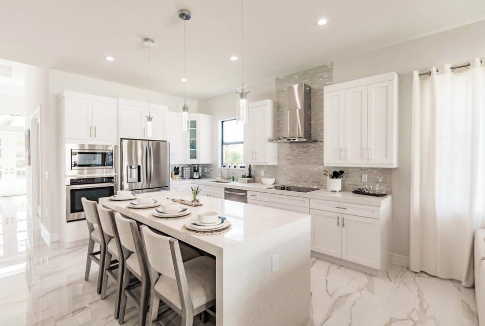 Sleek white cabinetry paired with a massive waterfall island and stainless steel appliances.