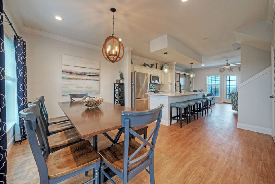 Gather around the dining table for shared meals, with coastal accents and balcony views nearby.