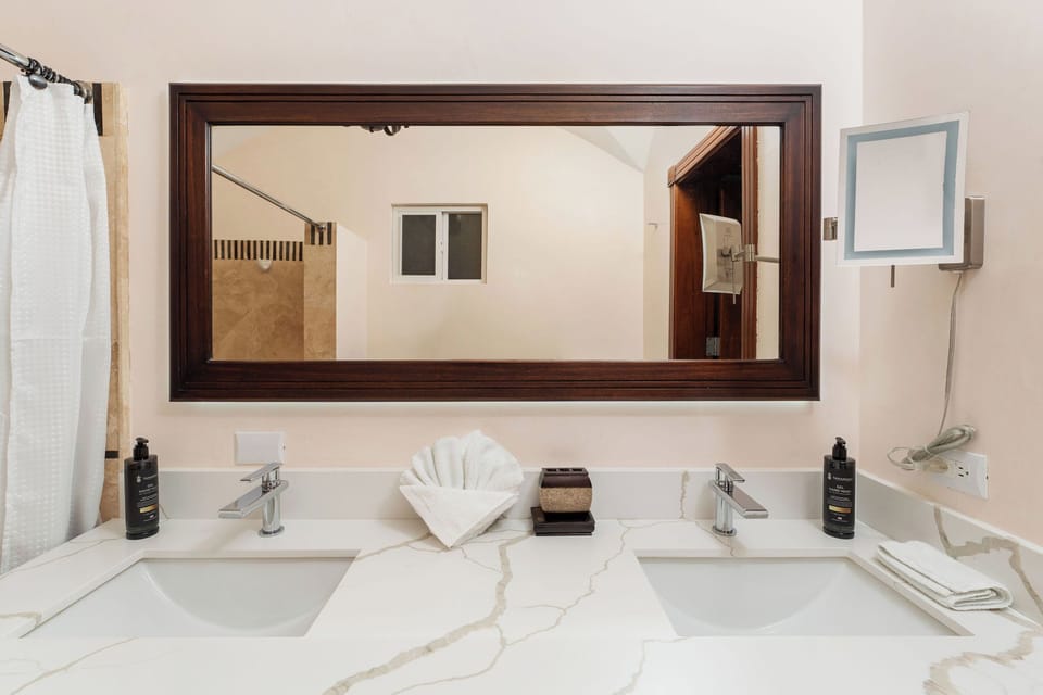Elegant master bathroom with dual sinks, coastal decor, and stylish finishes at Playa Langosta condo in Tamarindo, Costa Rica. Accessed through walk-in closet, bright natural light, serene atmosphere, perfect for romantic getaways.