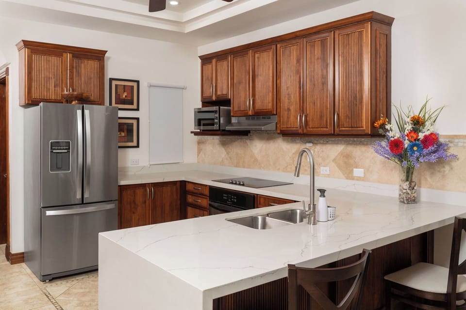Modern fully equipped kitchen with stainless steel appliances, coffee maker, blender, and cookware at luxury Playa Langosta condo, Tamarindo, Costa Rica. Perfect for preparing delicious family meals during your stay.