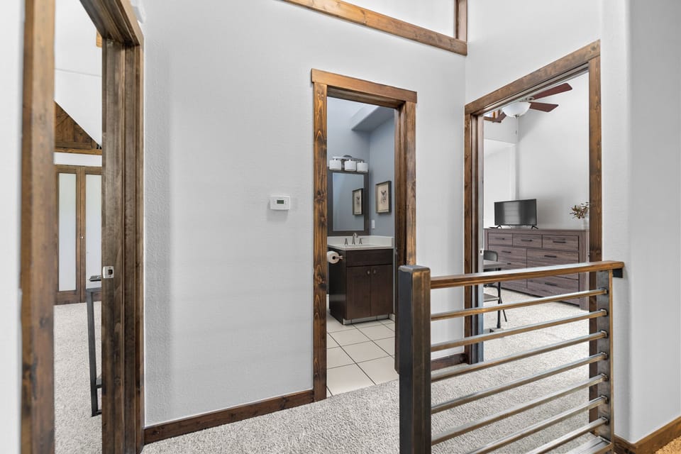 Spacious loft hallway connects you to restful private spaces, with warm wood tones and bright, airy design inviting you to settle in.