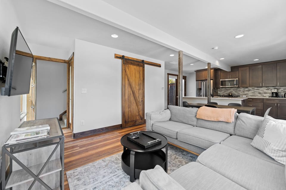 Unwind in this modern open-concept living space, where rustic barn doors and warm wood floors create a welcoming retreat. Sink into the plush sofa and enjoy your home away from home.
