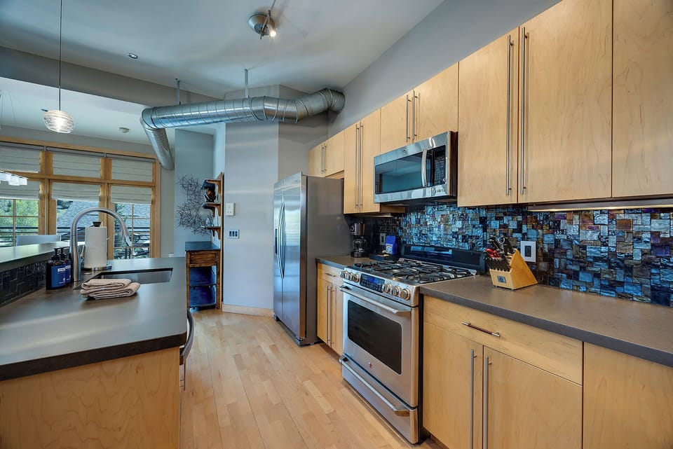 Your culinary haven awaits with sleek stainless-steel appliances, ample cabinetry, and a stunning mosaic backsplash that adds artful charm to every meal you create.