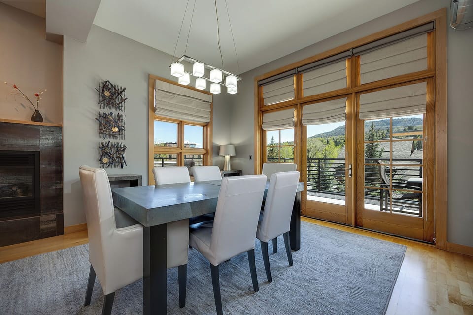 Gather around the sleek dining table with seating for six, where large windows frame stunning mountain views and fill your space with natural light.