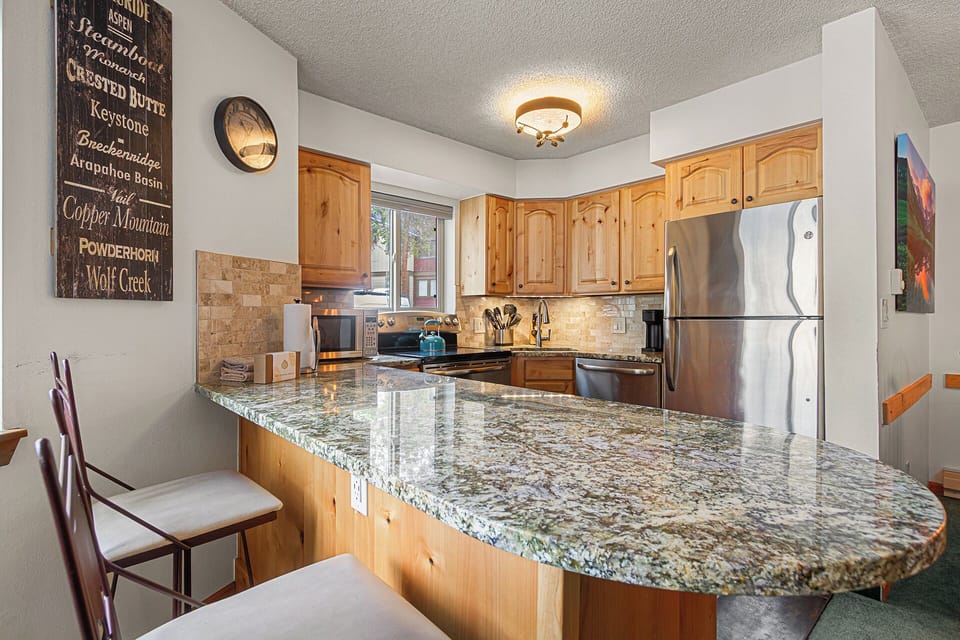 Your fully equipped kitchen features granite countertops, stainless steel appliances, and warm wood cabinetry—ideal for preparing meals together before hitting the slopes.
