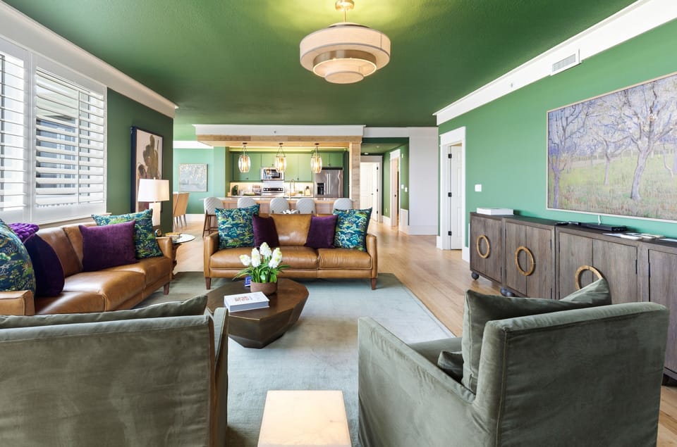 Sink into luxurious leather seating surrounded by vibrant emerald walls and artistic touches that create your perfect urban retreat.