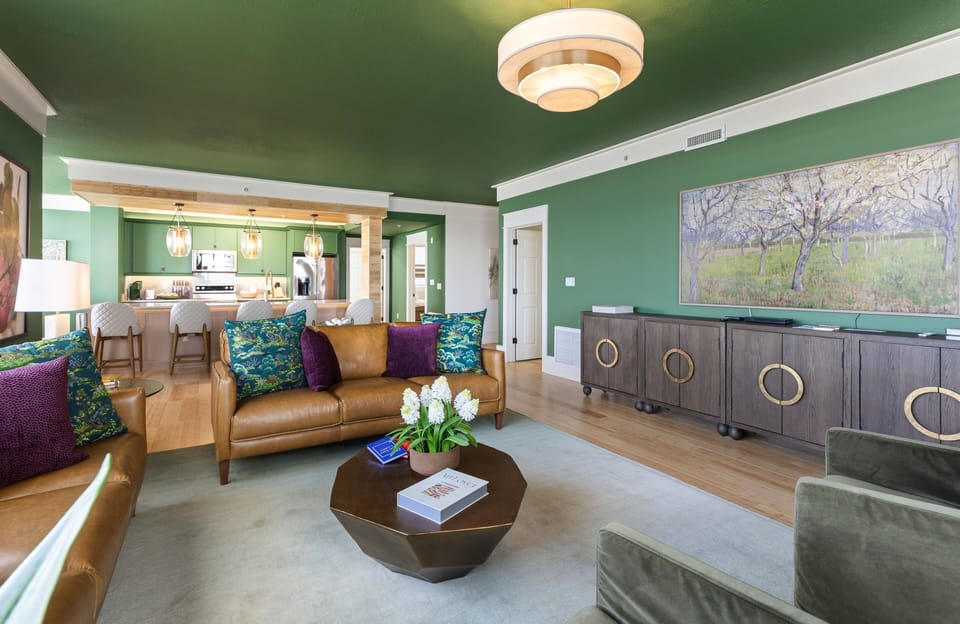 Relax in your stylish living room with vibrant emerald walls, leather seating, and modern art creating a sophisticated retreat.