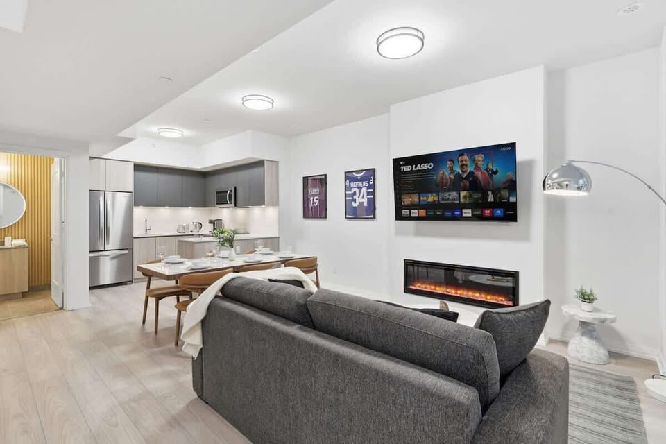 Bright living room with Smart TV, fireplace, and cozy seating by large windows