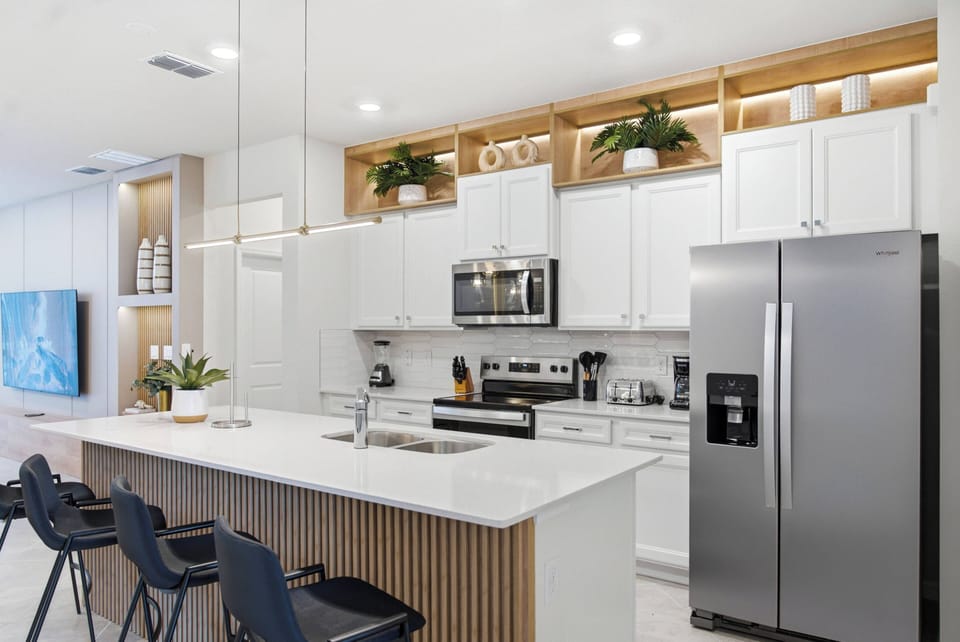 Bright and airy, this kitchen features sleek white cabinetry complemented by warm wood accents. The spacious island invites casual dining, while modern stainless steel appliances promise convenience for your culinary adventures.