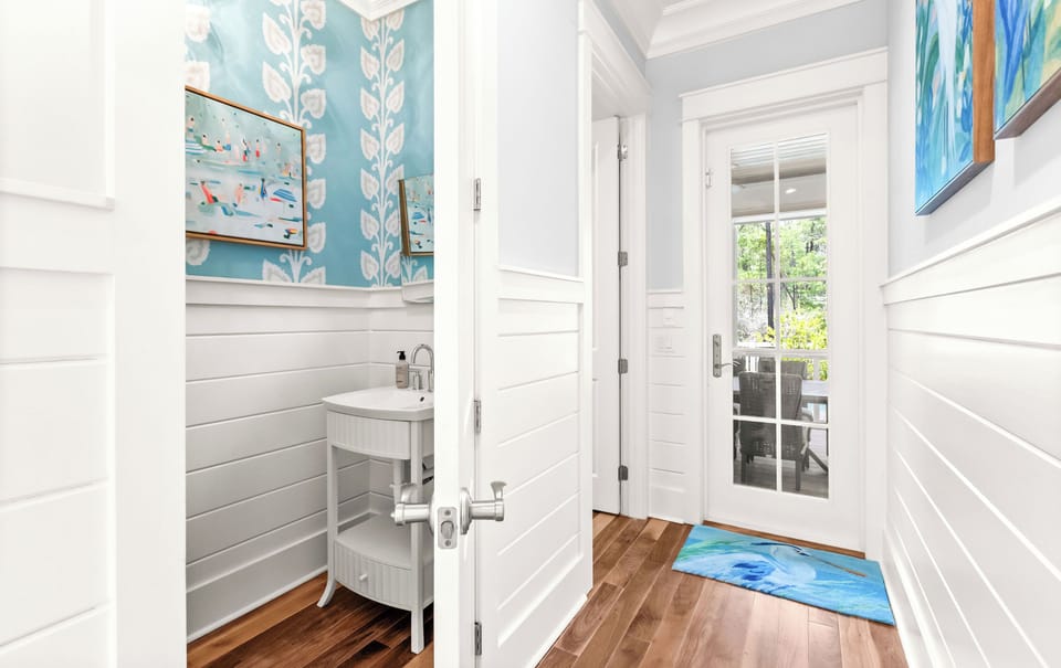 Step inside to find cheerful coastal décor, shiplap walls, and warm wood floors—your welcoming retreat awaits just beyond these bright French doors.