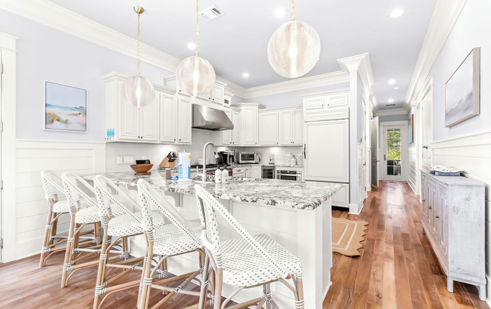 A stunning chef's kitchen awaits you with gleaming counters, custom white cabinetry, and island seating for casual meals with your group.