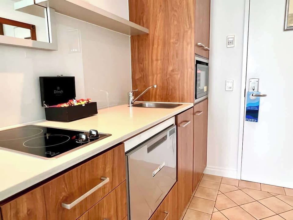 The studio features a compact kitchen equipped with modern amenities, including stove, microwave, fridge and a convenient dishwasher for easy cleanup. Perfect for quick meals and light cooking.