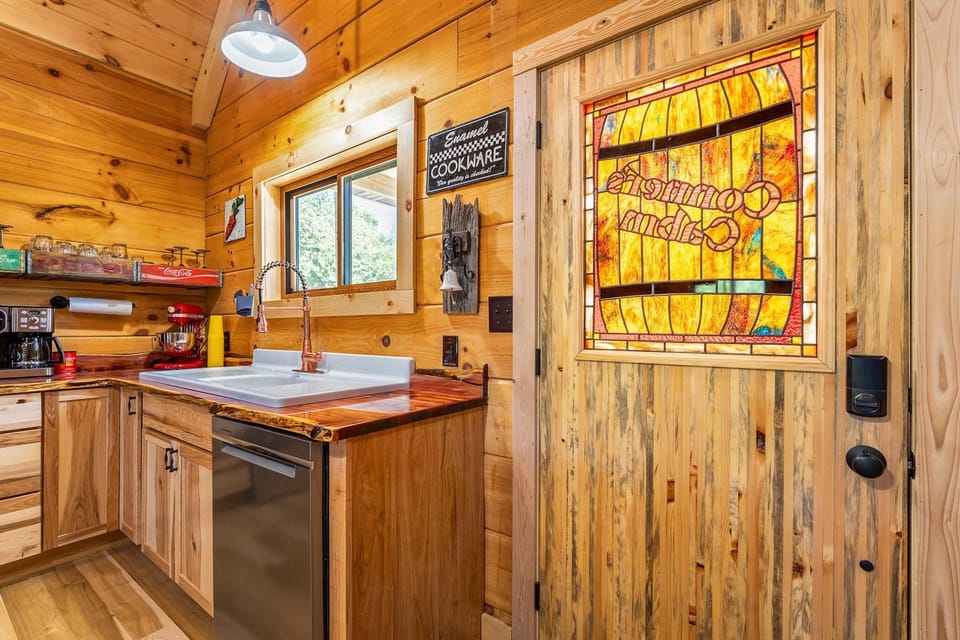 Kitchen corner with live-edge wood countertops, a white farmhouse sink, copper spring faucet, and stained glass door panel.