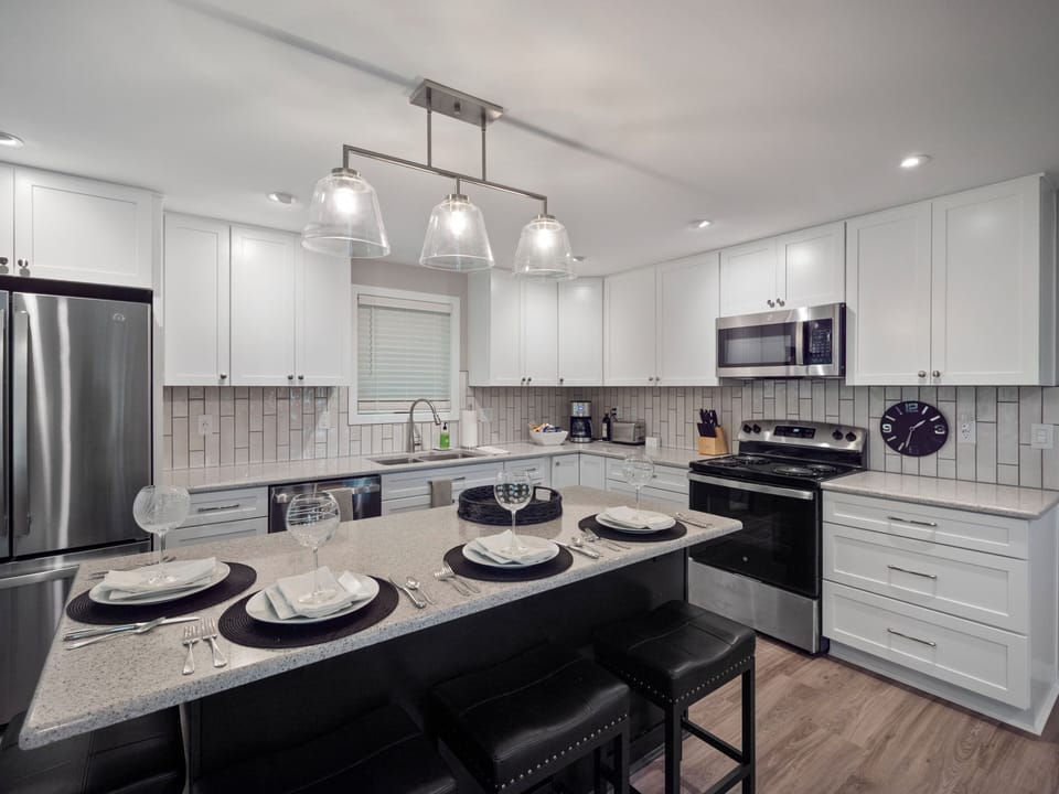 Kitchen area with large island, quartz counters, new stainless steel appliances.