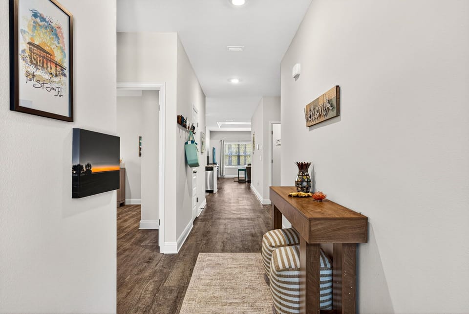 Step into this bright, welcoming hallway that guides you through your stylish retreat. Clean lines, warm wood floors, and thoughtful art create a serene entry into your comfortable home away from home.