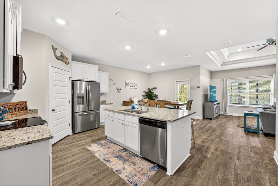 Your fully equipped kitchen features granite counters, stainless steel appliances, and a spacious island—perfect for preparing meals and gathering with loved ones in this bright, open space.