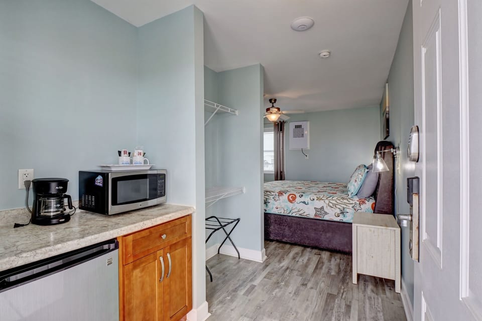 Efficient kitchenette with coffee maker, microwave, and mini fridge, flowing into a cozy king sleeping area; ideal for a comfortable and convenient coastal stay